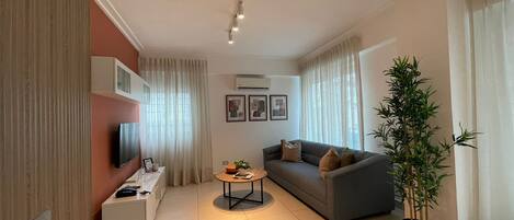 Una sala de estar moderna con un sofá, una mesa de centro, un televisor y una planta en maceta.