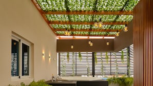 A modern outdoor seating area with a wooden bench, a sofa, and potted plants. - Central Park Tower (Santo Domingo)