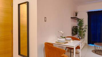 Un comedor moderno con una mesa blanca, sillas anaranjadas y un espejo grande en la pared.