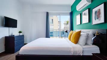 Un dormitorio moderno con una cama grande, un televisor de pantalla plana, un aparador y vistas de la ciudad a través de un ventanal.