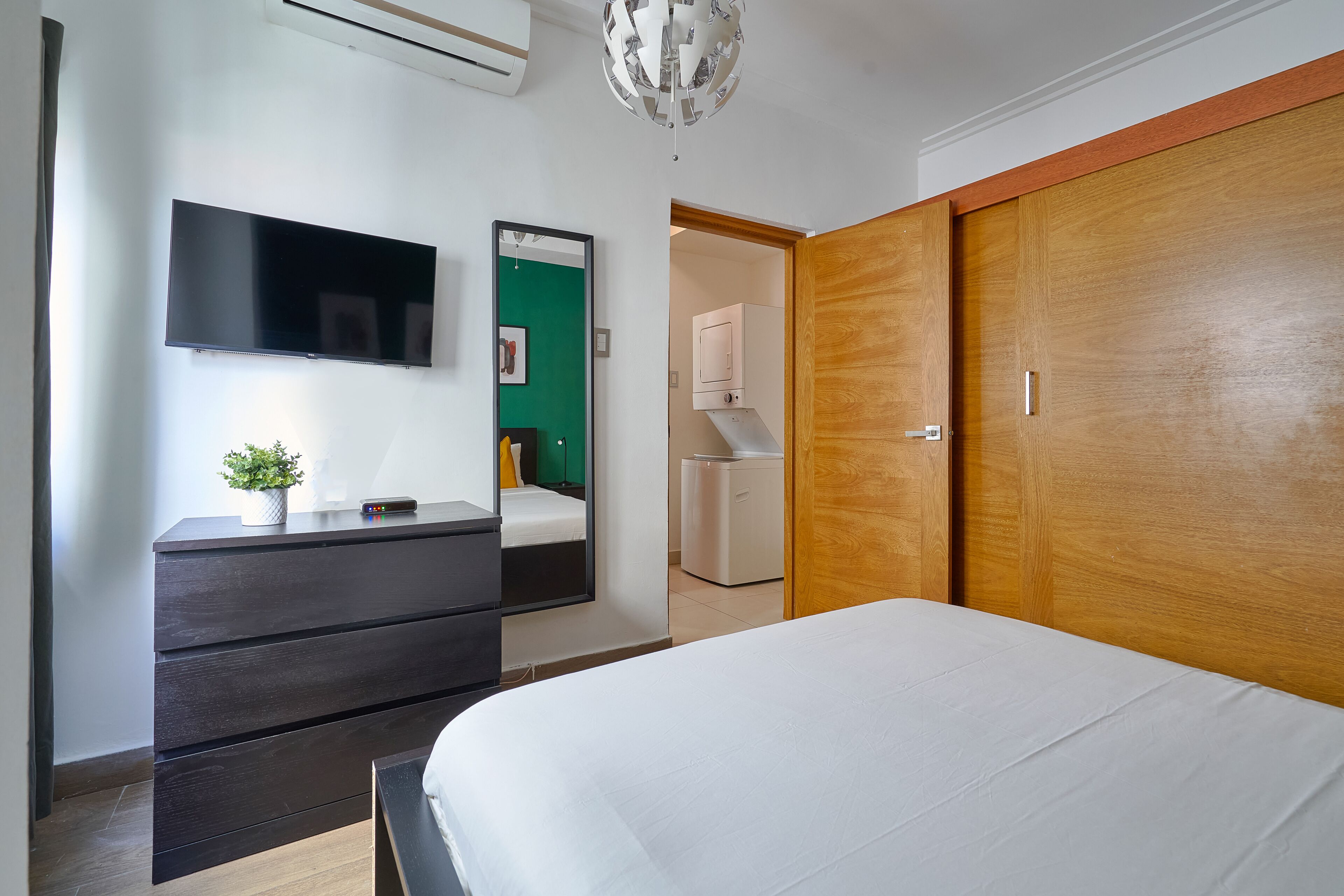 Une chambre d’hôtel moderne équipée d’un lit, d’une commode, d’un téléviseur à écran plat, d’un miroir et d’une armoire.