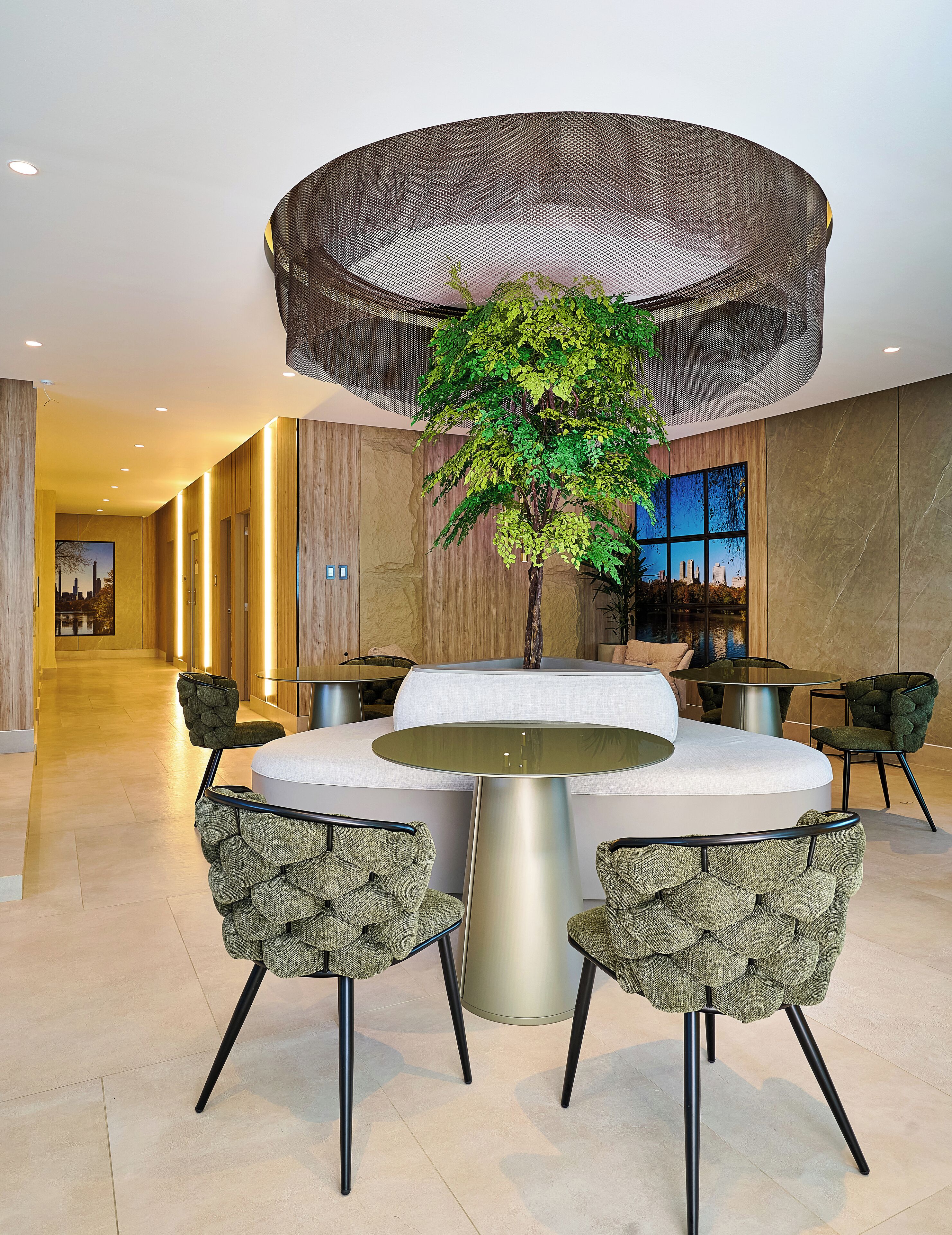 A modern dining area with a round table, four upholstered chairs, and a central plant.