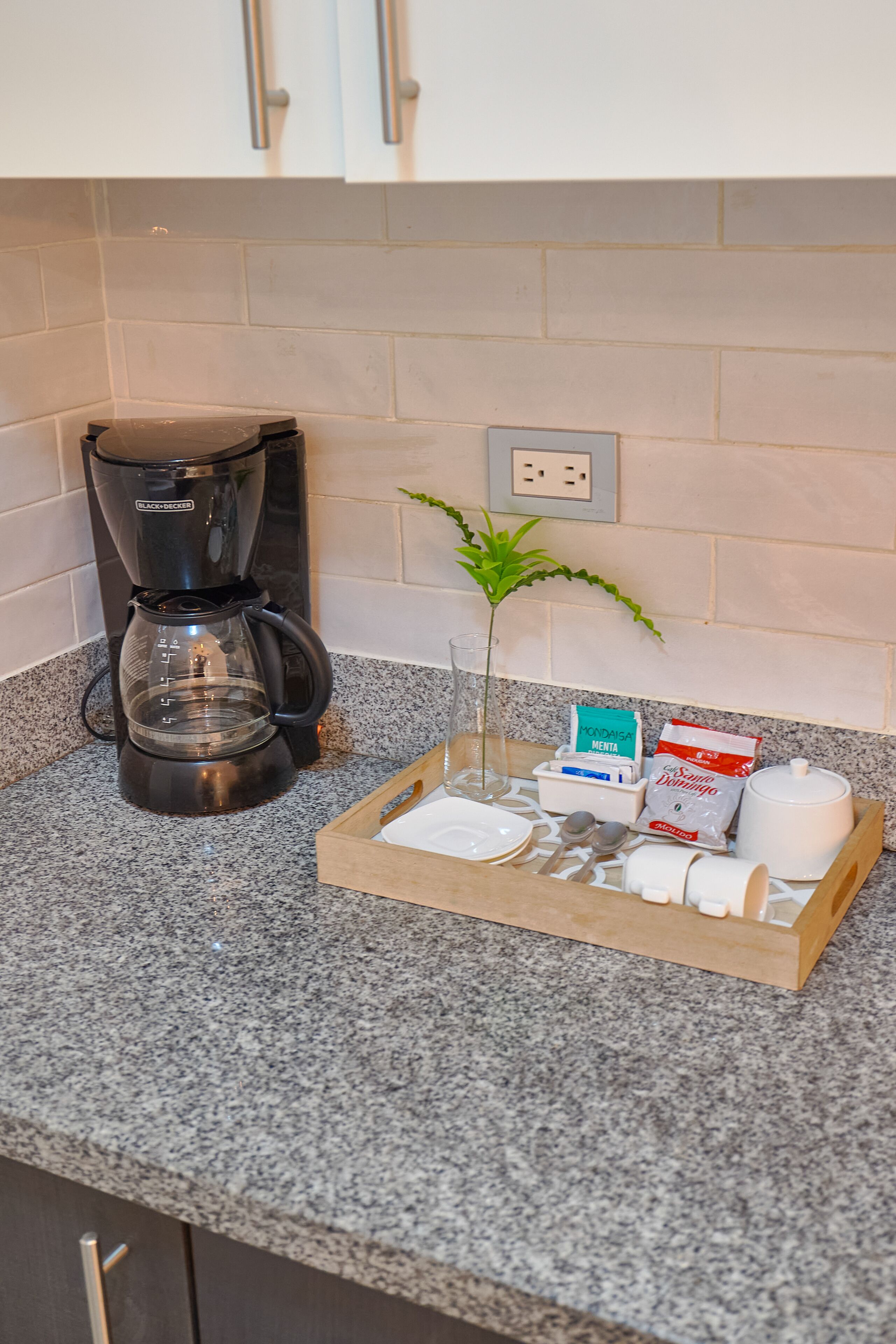 Een keukentrap met een koffiezetapparaat, een glas water, een plant en een dienblad met keukengerei en etenswaren.