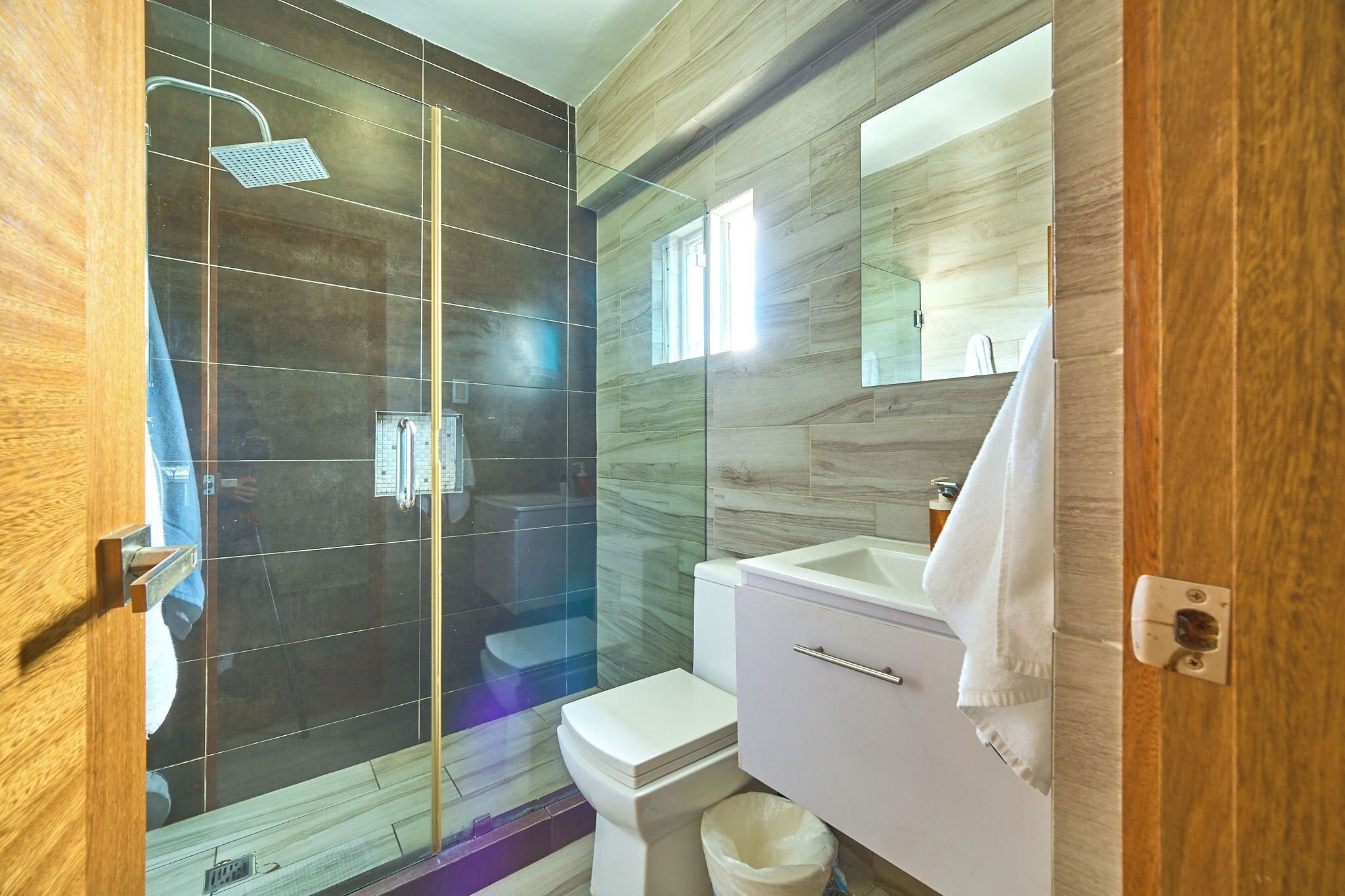A modern bathroom with a glass shower enclosure, a white toilet, and a vanity with a mirror.