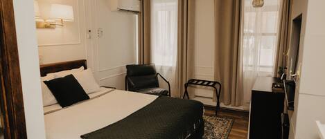 Ein Hotelzimmer mit einem großen Bett, einem Schreibtisch, einem Stuhl und einem kleinen Tisch.