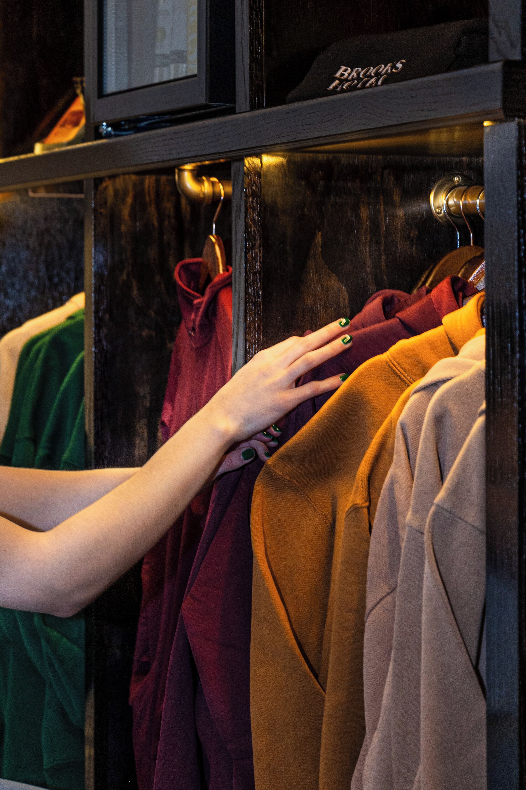 A hand selecting a coat from a rack in a hotel setting.