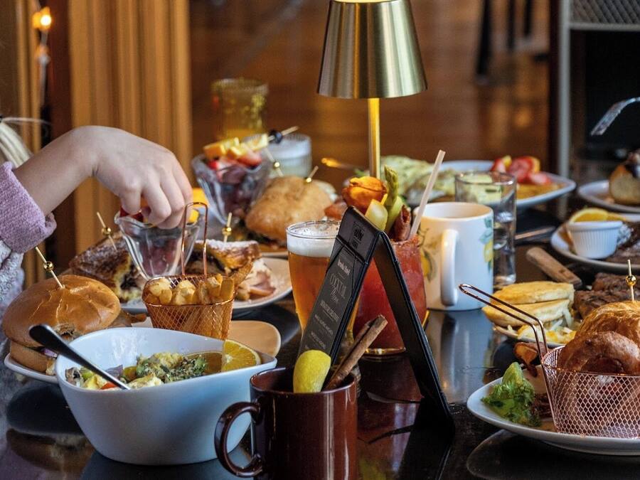 A table set with various dishes, drinks, and a cocktail menu stand.