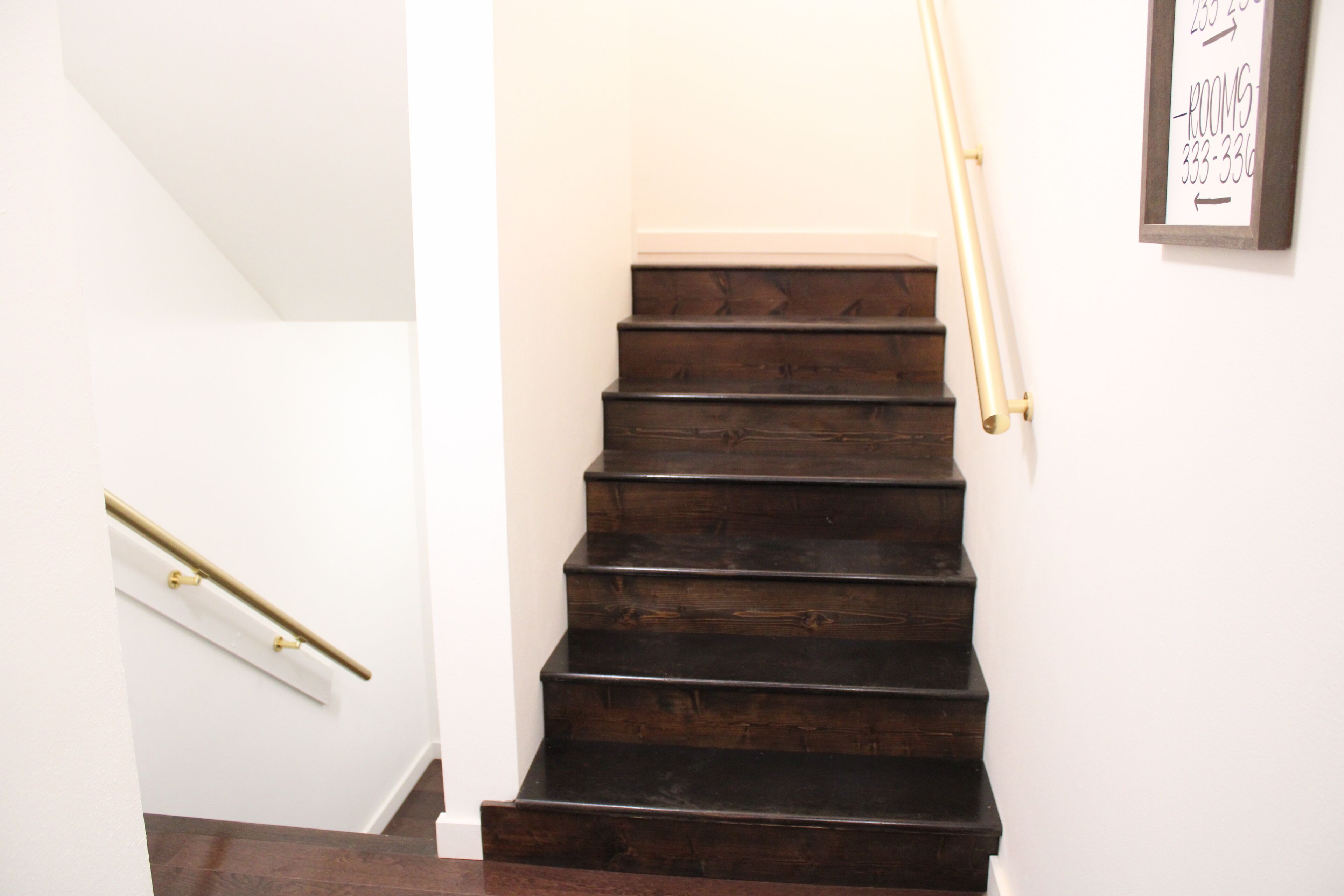 Una escalera con escalones de madera oscura y una pared blanca.