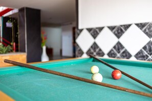 A pool table with a cue stick, three billiard balls, and a tiled wall in the background. - Hotel Sevilla Plaza Bucaramanga (Bucaramanga)