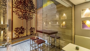 Ein modernes Interieur mit Glastrennwand, Holzstühlen, einem weißen Tisch und Wandleuchten.