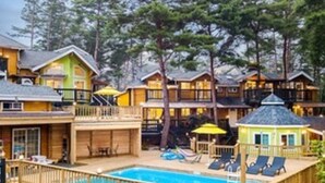 A resort with multiple wooden cabins, a swimming pool, and outdoor seating areas. - Castle of Magic Pension (Hoengseong)