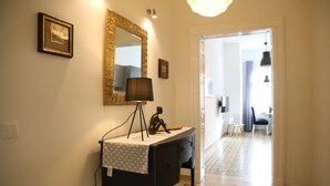 A hallway with a black console table, a mirror, and a lamp. There is a door leading to another room.