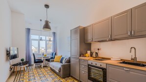 A compact kitchen with grey cabinets, a wooden countertop, and a built-in oven.