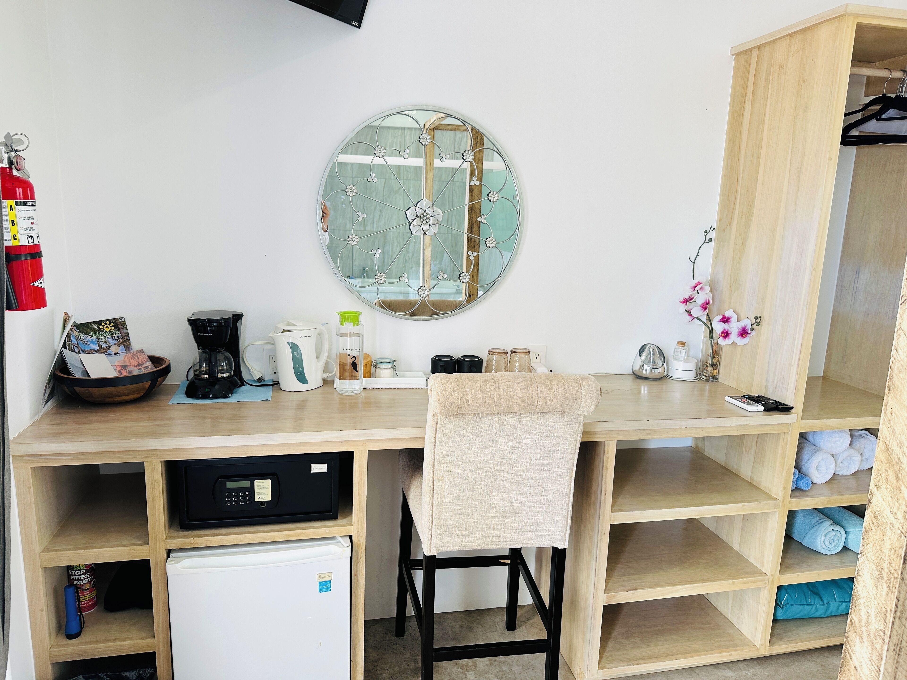 Una kitchenette compacta con cafetera, hervidor y un refrigerador pequeño.