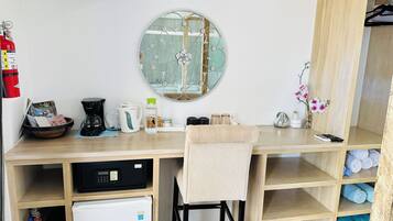 Una kitchenette compacta con cafetera, hervidor y un refrigerador pequeño.