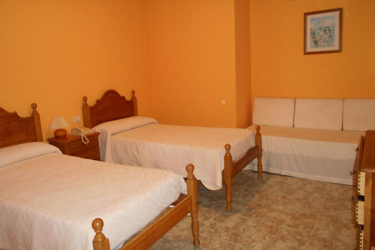 Ein Hotelzimmer mit zwei Einzelbetten, einem Nachttisch mit Lampe, einem Telefon und einem Bild an der Wand.