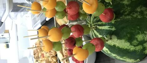 Obstspieße mit Wassermelone und verschiedenen Früchten auf einem Teller, neben einer großen Wassermelone.