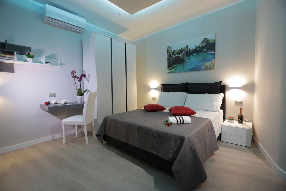 Una camera da letto moderna con un letto, un comodino e una scrivania.