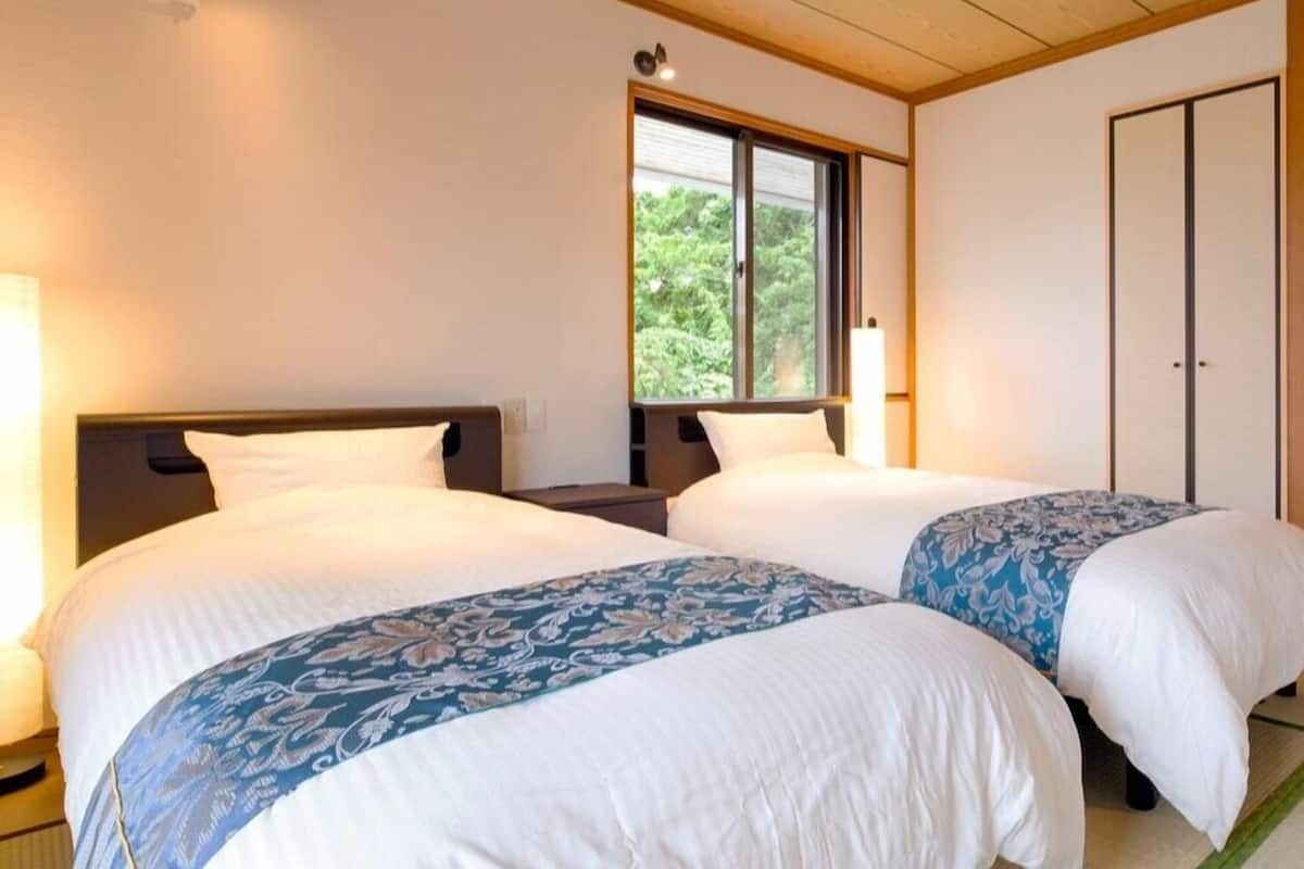 Habitació d'hotel amb dos llits, una finestra que dona a zones verds i un armari.