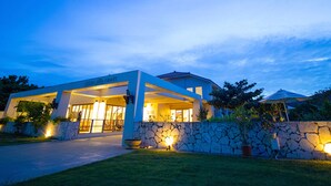 Een modern huis met een gevel van natuursteen, grote ramen en een overdekte veranda.