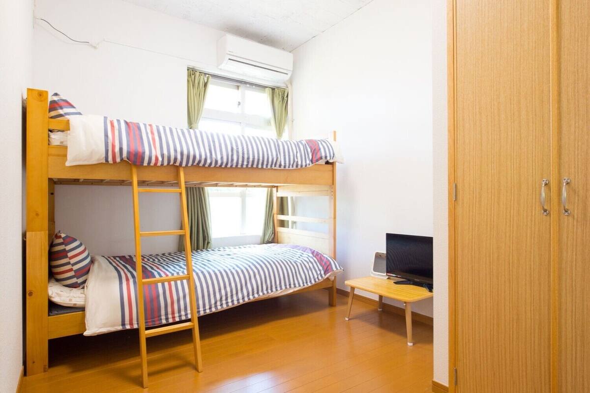 Habitació amb lliteres, una taula i una televisió.