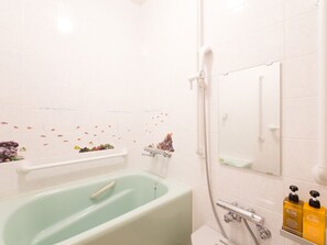 Een badkamer met een groen bad, een wit toilet, een douchegedeelte en een spiegel.