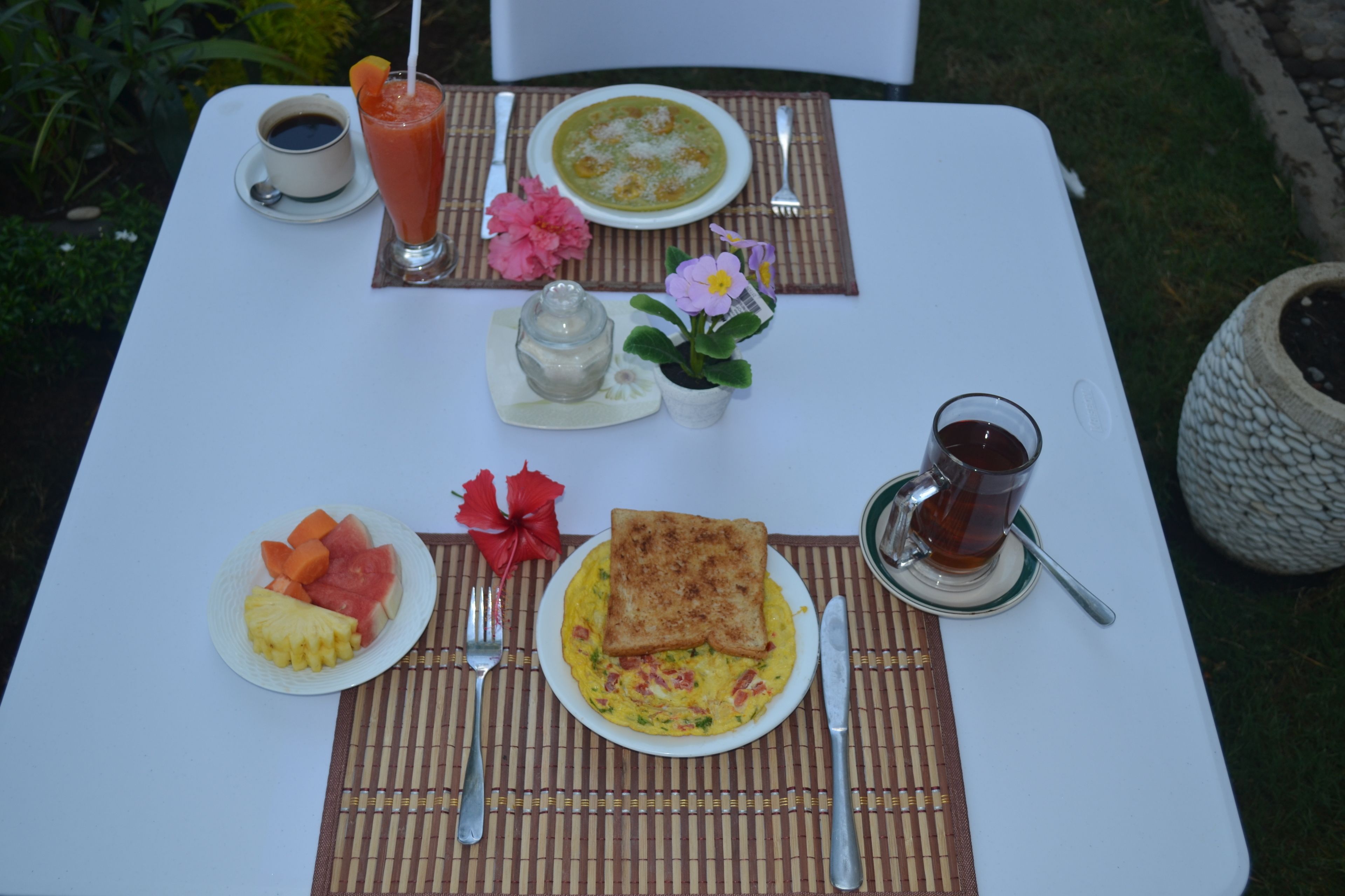 A table set with breakfast including toast, eggs, fruit, and beverages.