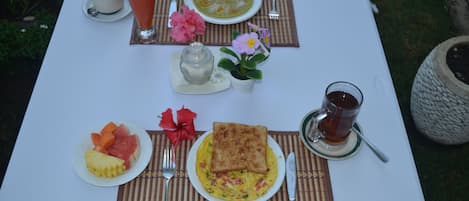 Une table dressée pour le petit-déjeuner, avec des toasts, des œufs, des fruits et des boissons.