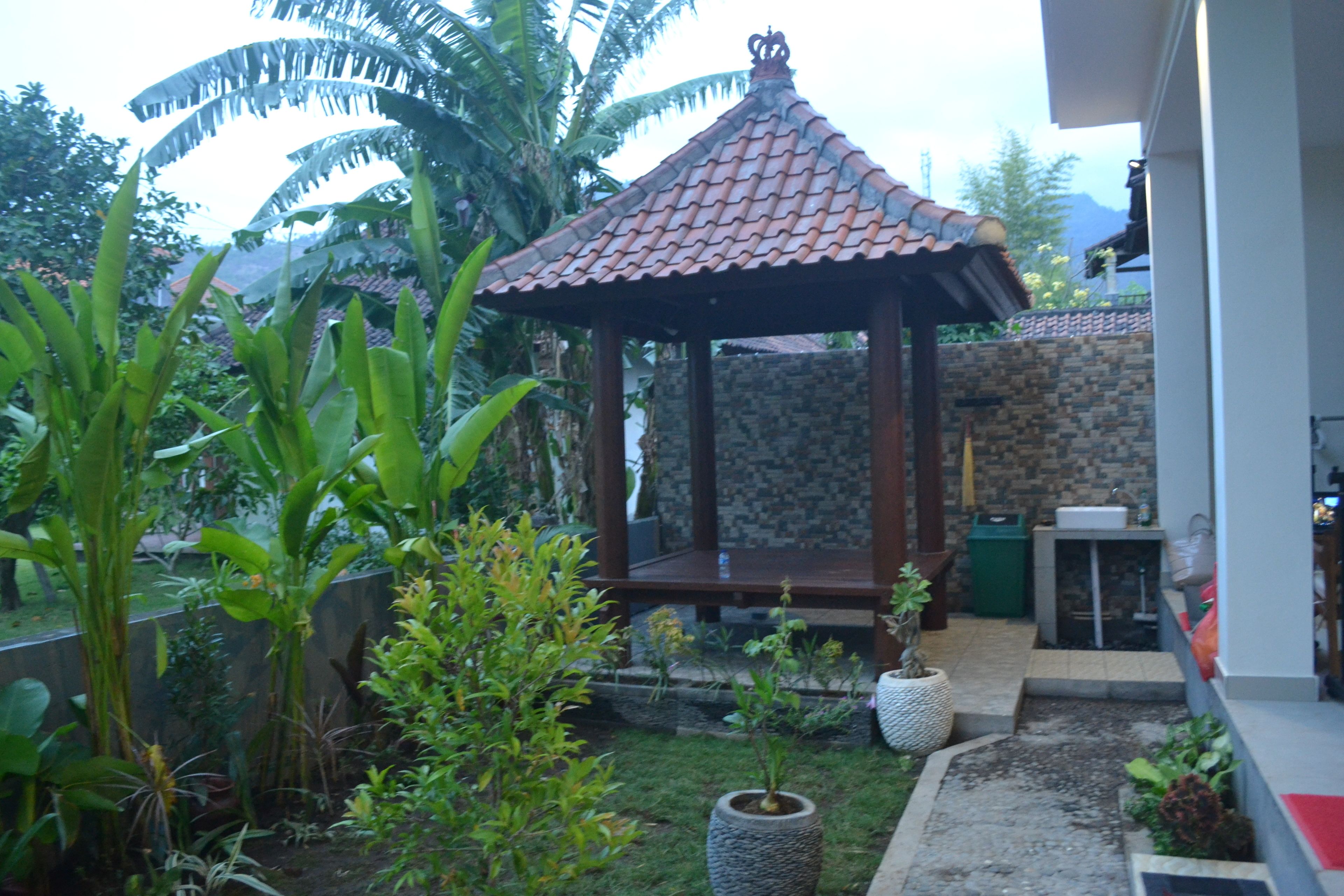 A garden with a gazebo, stone wall, and potted plants.