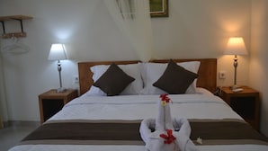Habitación de hotel con una cama bien hecha, dos lámparas de noche, un cabecero de madera y un perchero en la pared.