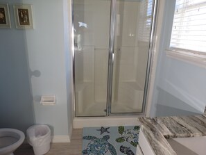 Une salle de bain avec une douche à parois de verre, des toilettes et un lavabo.