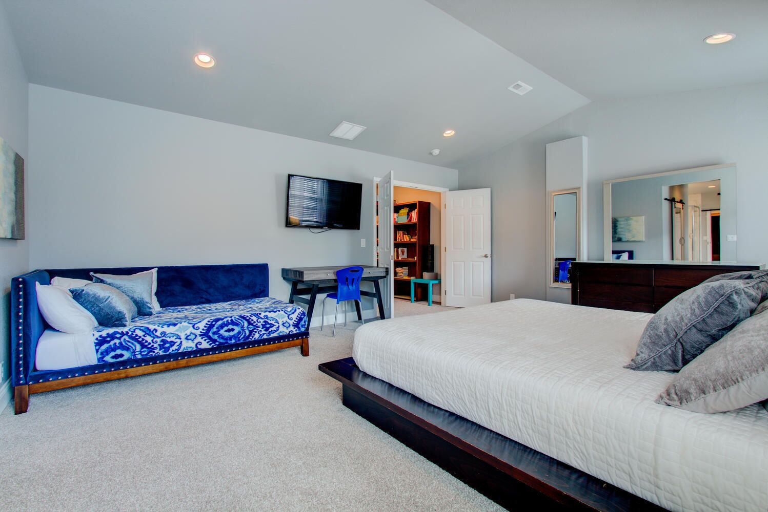 A bedroom with a large bed, a sofa, a desk, and a TV.