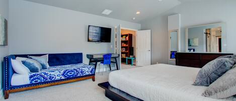 A bedroom with a large bed, a sofa, a desk, and a TV.