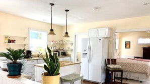 A compact kitchen with white cabinets, a refrigerator, and a dining area with a table and chairs.