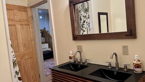 A bathroom with a double sink, wooden vanity, and a large mirror.