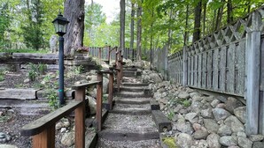 A wooden pathway with railings, surrounded by rocks and trees.