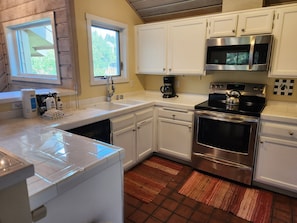 A kitchen with white cabinets, a stainless steel oven, a microwave, and a coffee maker. - Snowcreek Resort Vacation Rental 302 (Mammoth Lakes)