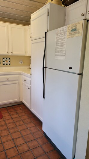 A kitchen with white cabinets, a white refrigerator, and a tiled floor. - Snowcreek Resort Vacation Rental 302 (Mammoth Lakes)