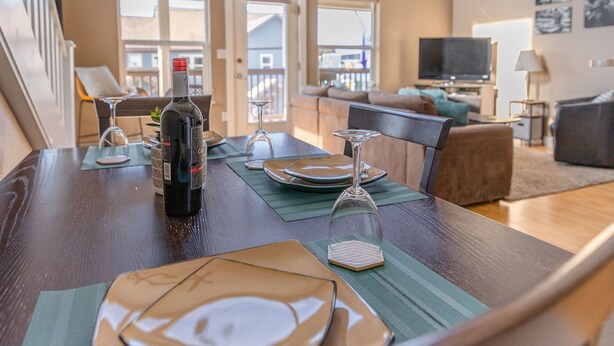 Een eethoek met een tafel voor twee, een fles wijn en een televisie op de achtergrond.