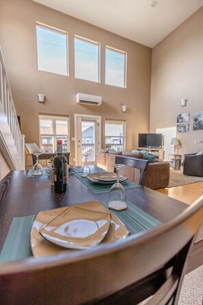 A dining area with a table set for two, a bottle of wine, and a television in the background.