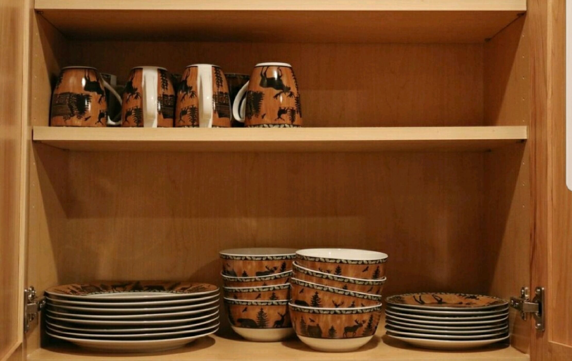 A wooden cabinet with shelves holding ceramic mugs and plates.