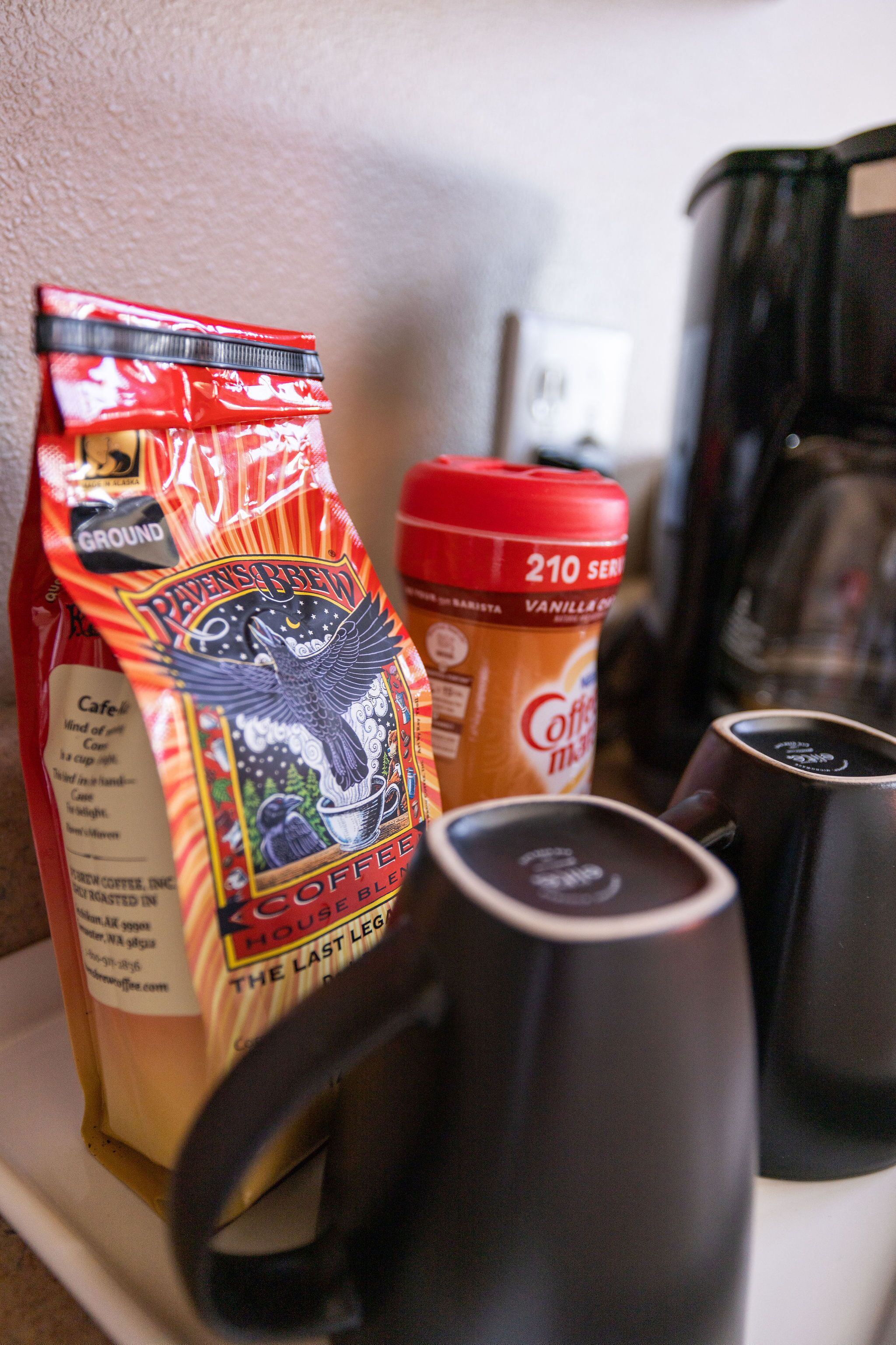 Eine Kaffeemaschine, eine Kaffeepackung und eine Kaffeeflasche auf einer Küchenarbeitsplatte.