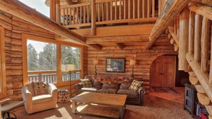 L’intérieur d’une cabane en rondins présente un espace de vie chaleureux, avec un canapé, un fauteuil et une table basse.