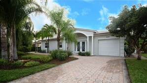 A residential house with a paved driveway, palm trees, and a garage.