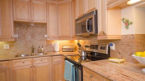 A kitchen with wooden cabinets, a stainless steel microwave, a toaster, and a stove.