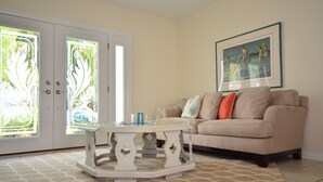 A living room with a beige sofa, a white coffee table, and a framed painting on the wall.