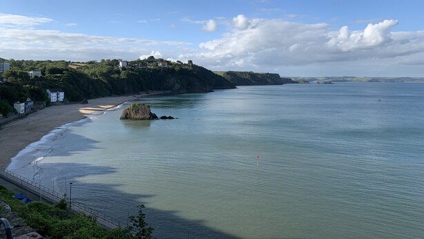 A coastal landscape with a beach, rocky outcrops, and buildings on a hillside. - Modernised traditional cottage, Sleeps 5,short walk to beaches, town, amenities  (Tenby)