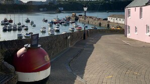A harbor with boats, a lighthouse, and a pink building. - Modernised traditional cottage, Sleeps 5,short walk to beaches, town, amenities  (Tenby)
