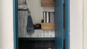 A bathroom with a white sink, wooden shelves, striped pillows, and a towel rack. - Modernised traditional cottage, Sleeps 5,short walk to beaches, town, amenities  (Tenby)