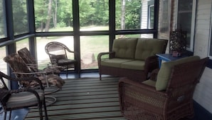 A covered porch with wicker furniture, a striped rug, and a view of a yard. - Charming Lake Cottage est 1903! Private and relaxing waterfront, family fun! (Rindge)